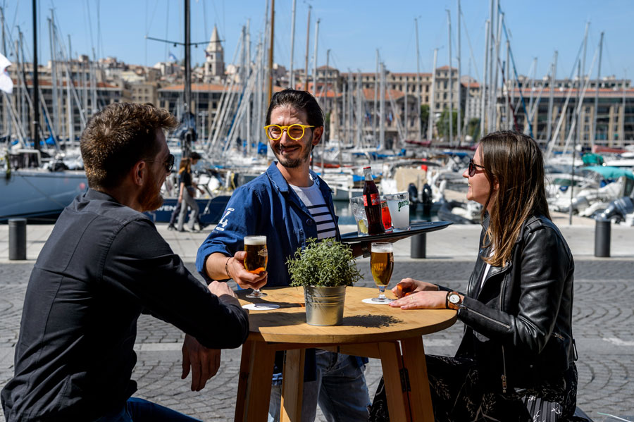 Un serveur apporte des bières en terrasse d'un bar-restaurant en bord de plage