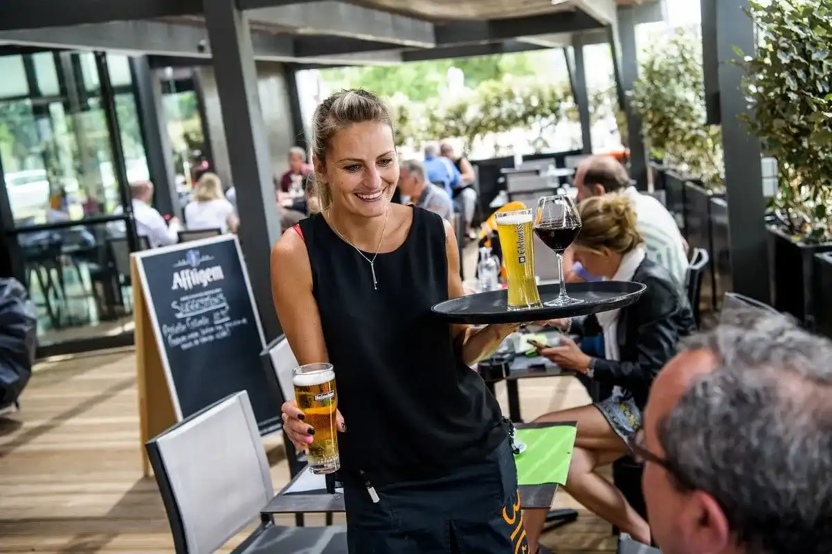 Serveuse apportant des bières pression à une terrasse de café